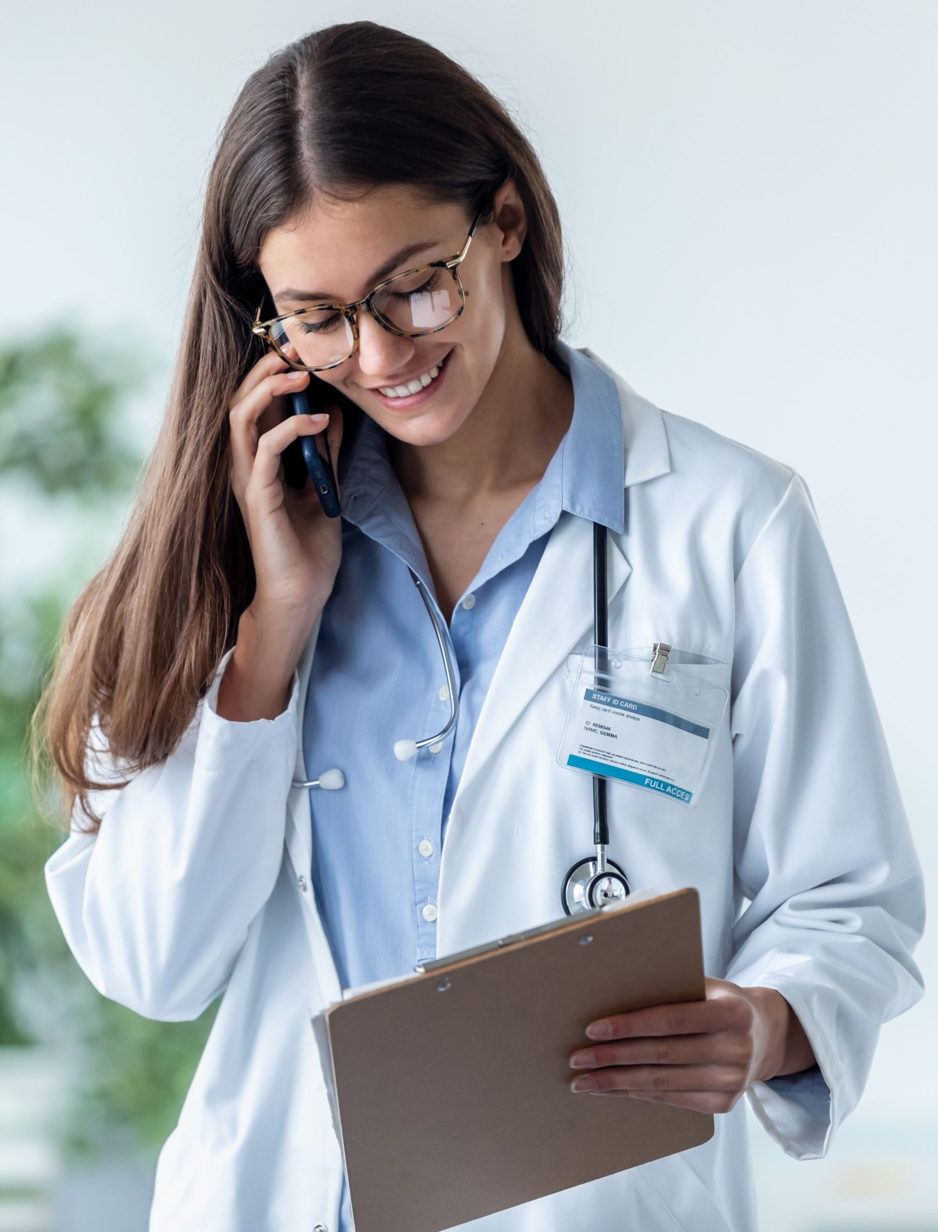 A female doctor is reading blood test results from a clipboard she is holding.