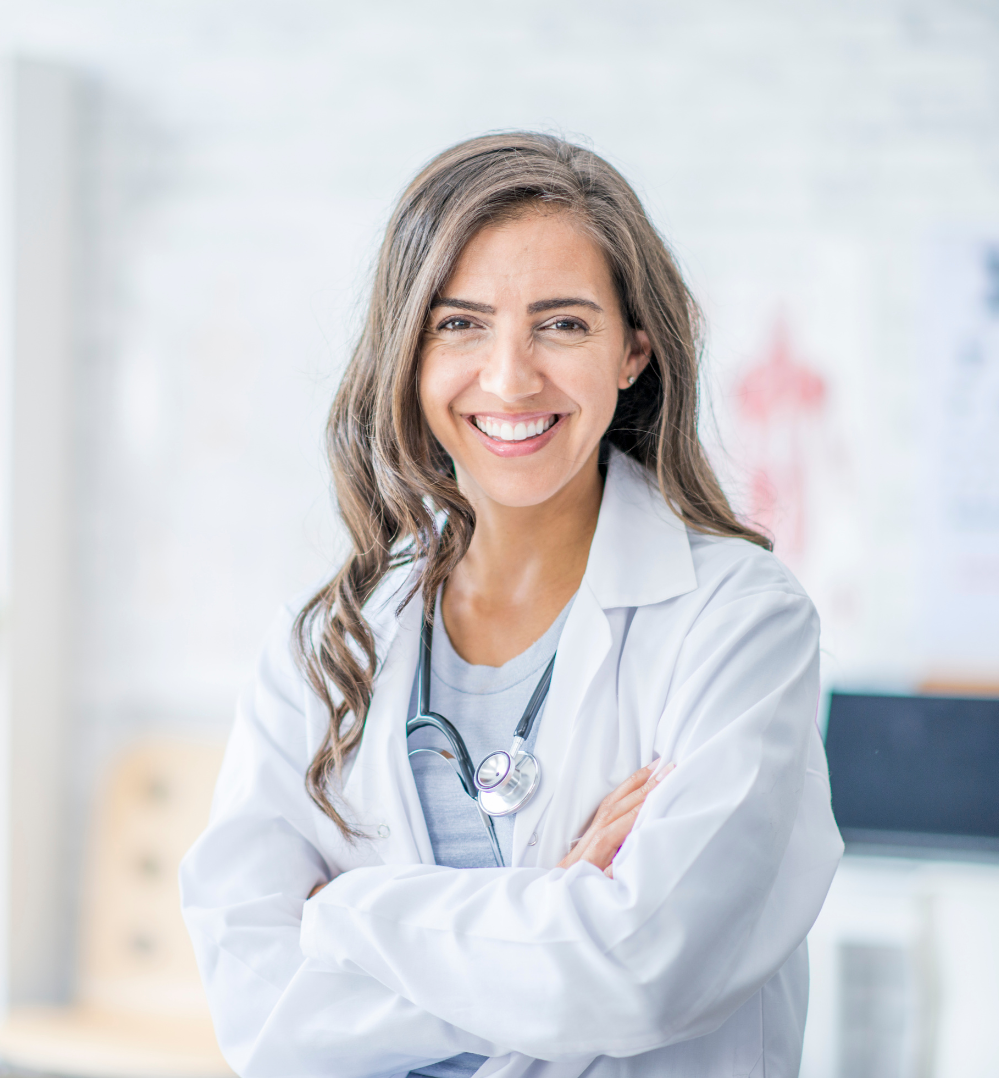 Female doctor in a white lab coat with a stethoscope around her neck. Her arms are folded and she's smiling.