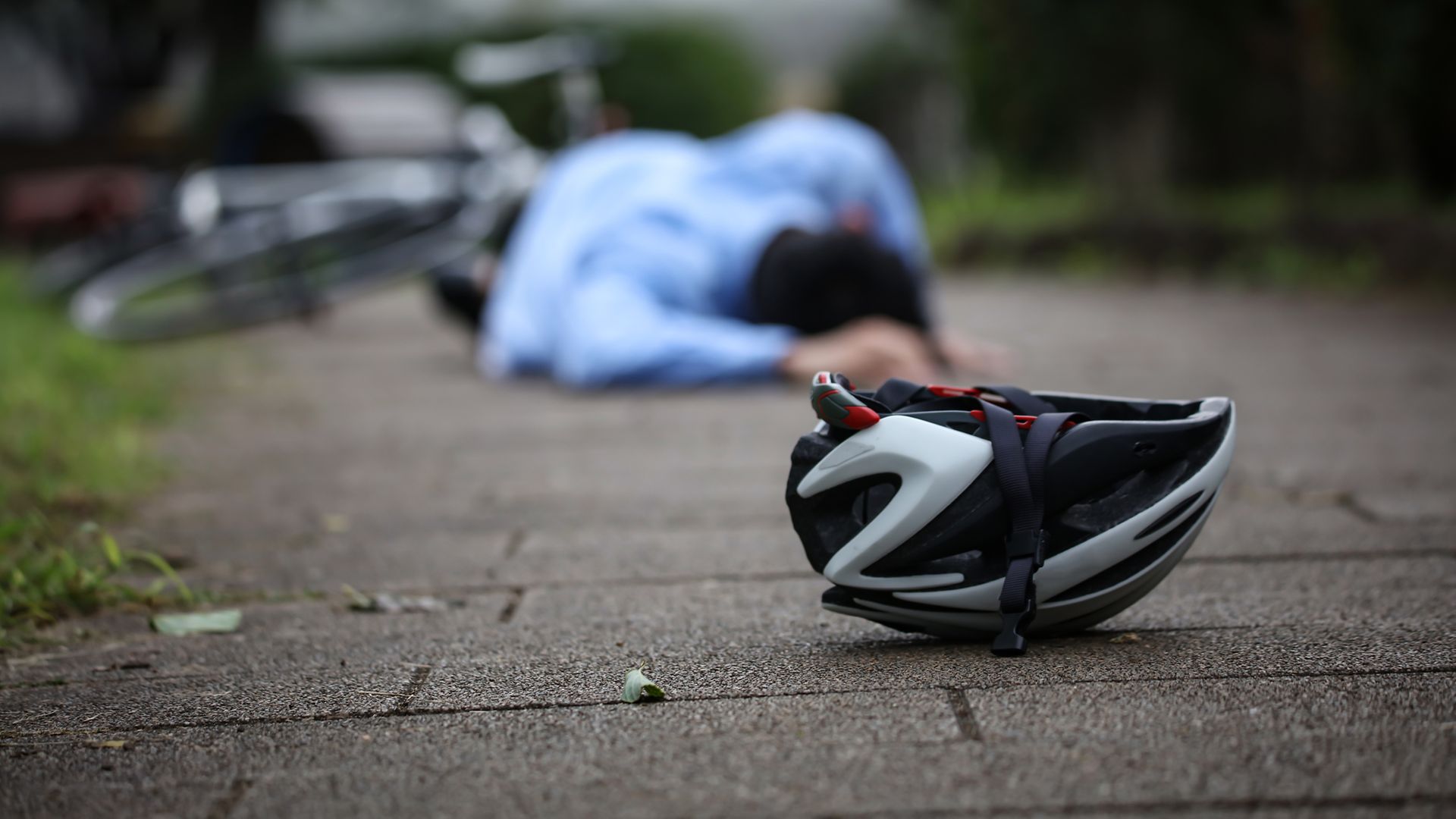 Ein Mann liegt neben einem Fahrradhelm auf dem Boden.