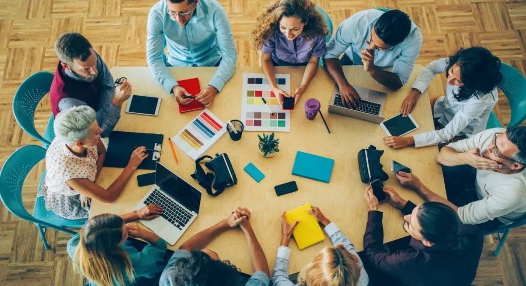 Persone attorno a un tavolo per un meeting intente a prendere appunti