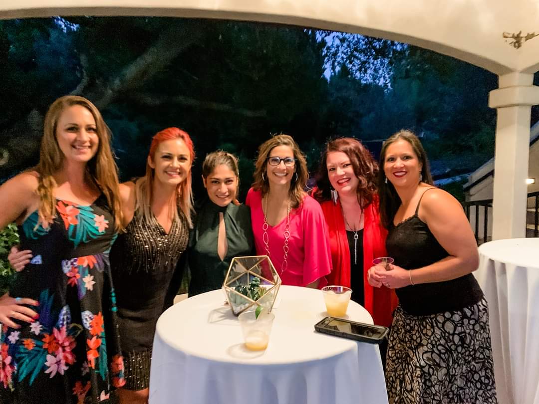 photo of 6 women around a table all dressed up