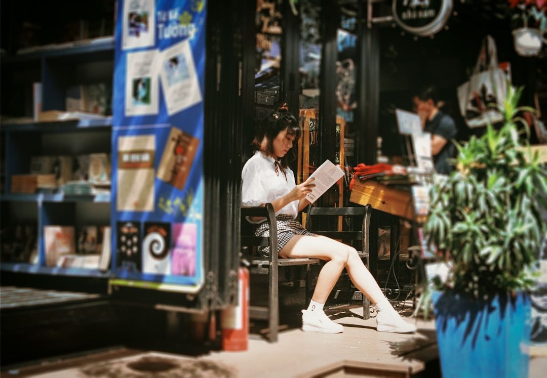 A woman sat reading by  bookstore/ coffee shop