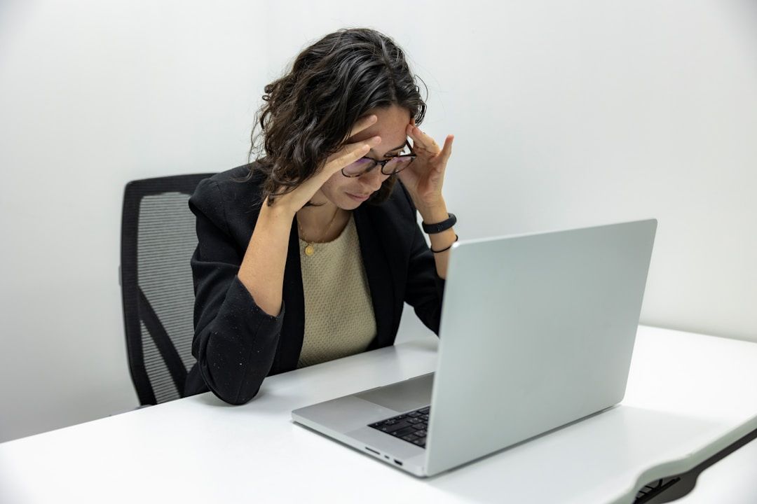 a picture of woman head in hands looking at laptop