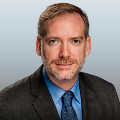 Rodger Baker wearing dark grey suit, blue shirt and grey-blue tie