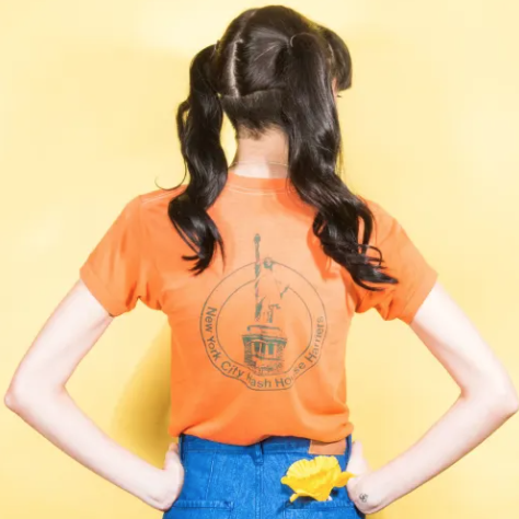 Young woman with her back to the screen and a yellow flower in her back pocket.