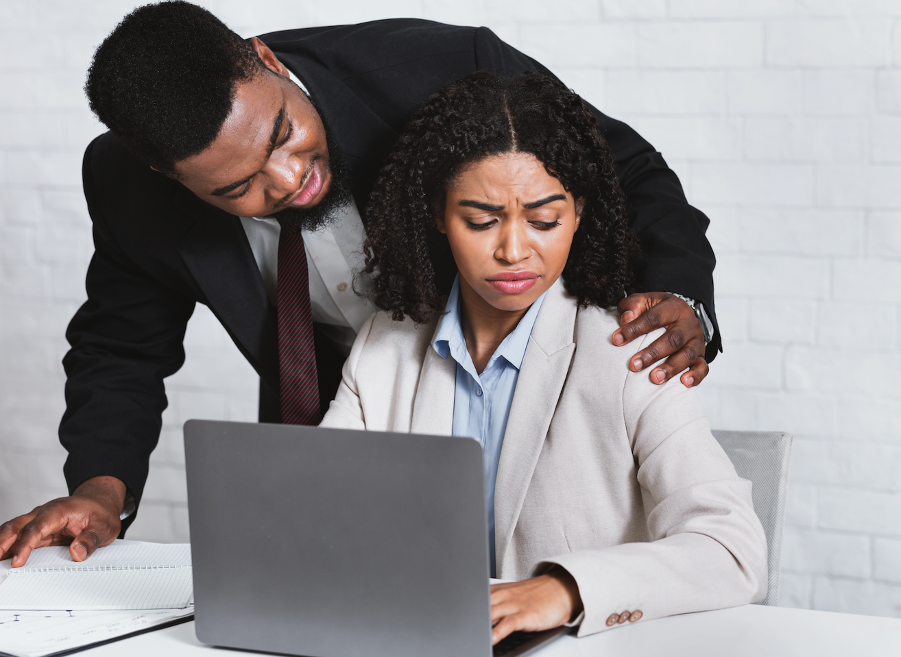 Workplace harassment depicted by a male colleague invading a female coworker's personal space, with her showing discomfort while working on her laptop. This image emphasizes the importance of professional boundaries, respect, and the need to address inappropriate behavior in the workplace.