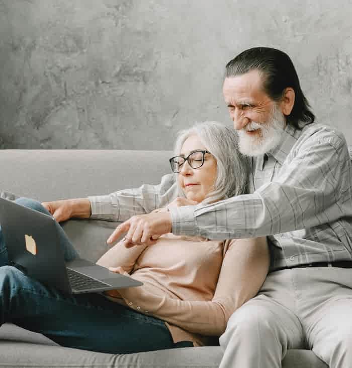 elderly couple in front of the laptop on a sofa