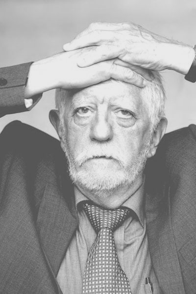 fatigued old man holding head