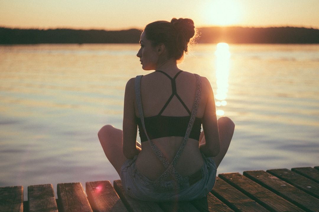 woman sitting on the dock of the lake at Camp Timber Trails at sunrise
