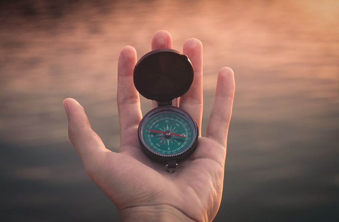 a hand holding a green compass as we discuss the gift of gene key 7: guidance