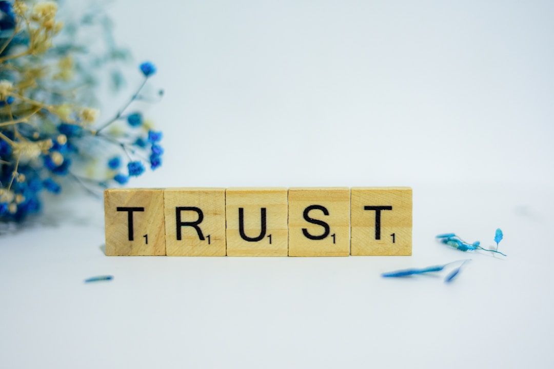 scrabble tiles lined up with flowers in the background - they say "trust" the siddhi of gene key 63