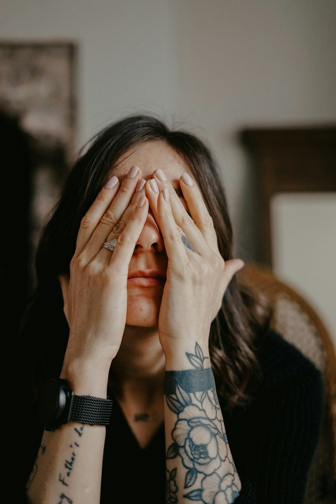woman holding her head in her hands with her hands covering her face like she is sitting in doubt, the shadow of gene key 63
