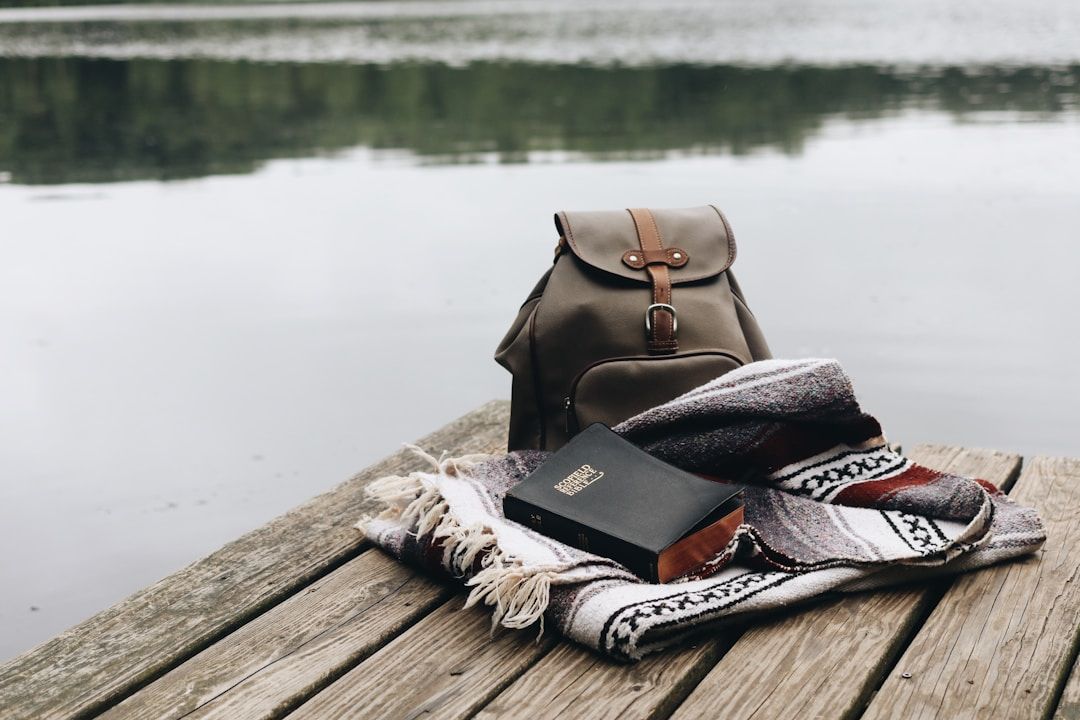 bag, blanket, and book sitting on a dock giving the vibe of relaxation and retreat