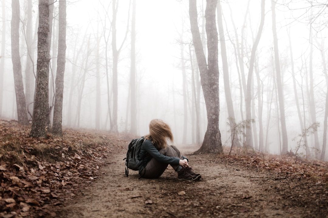 girl sitting in the foggy and gray woods looking lost and disconnected from the world symbolizing the shadow of gene key 25
