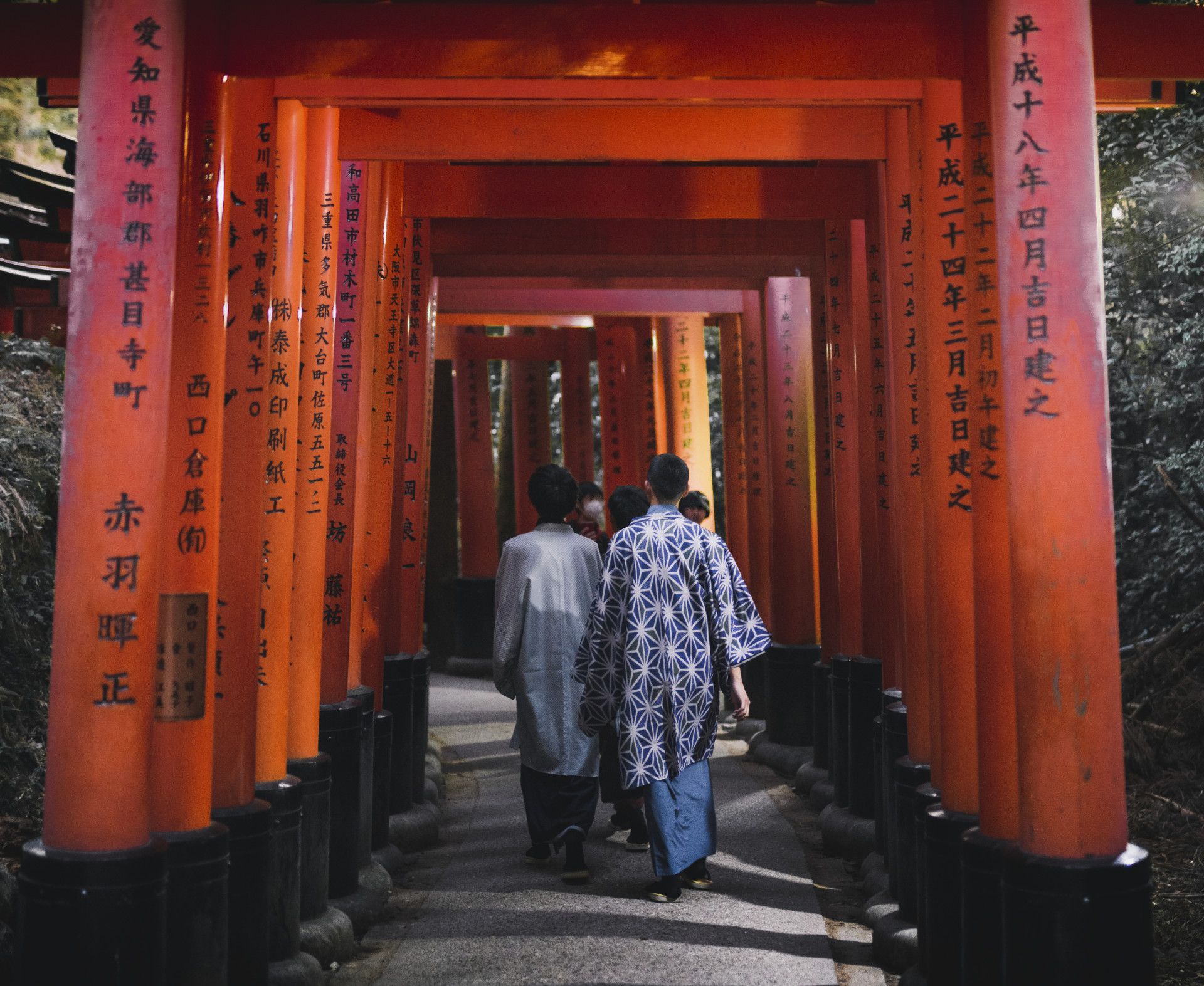 Visitors walking through red torii gates at Fushimi Inari Shrine in Kyoto, Japan