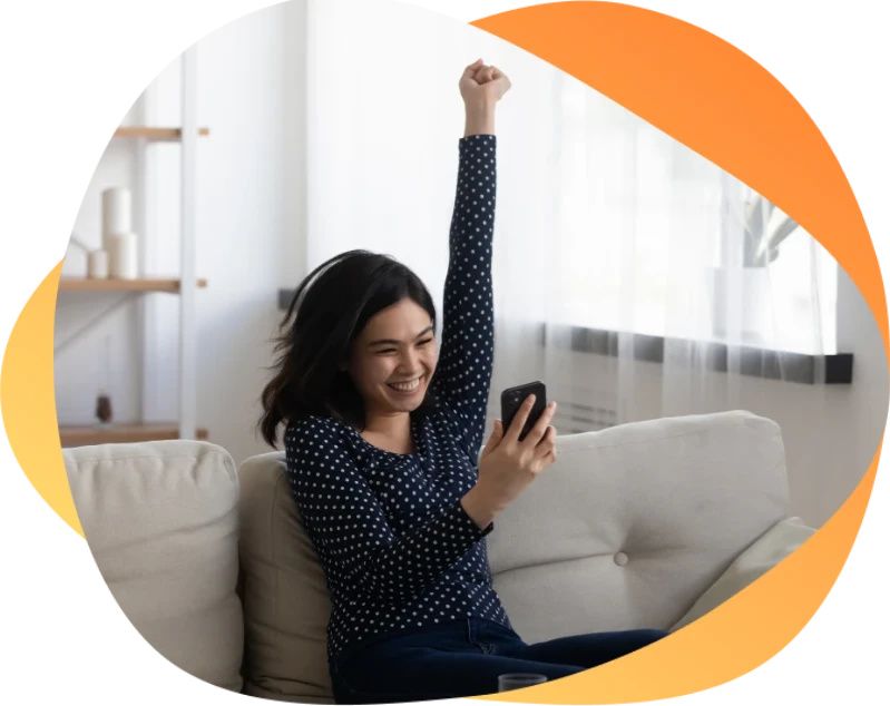 Smiling woman celebrating success while looking at phone