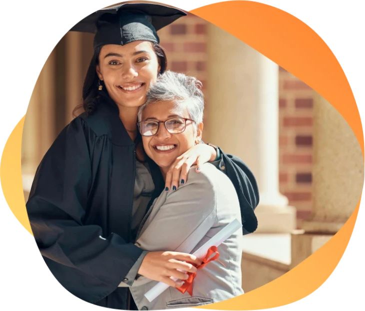 Happy graduate in cap and gown hugging family member after ceremony