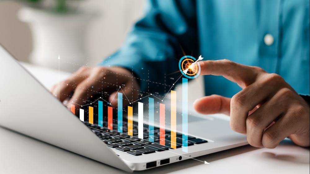 person using laptop with metrics graphics hovering above