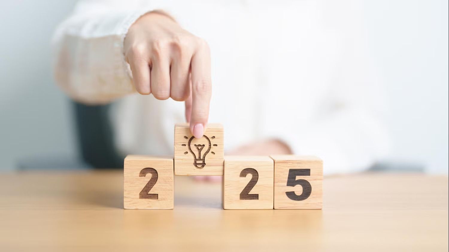 person placing wooden blocks spelling 2025