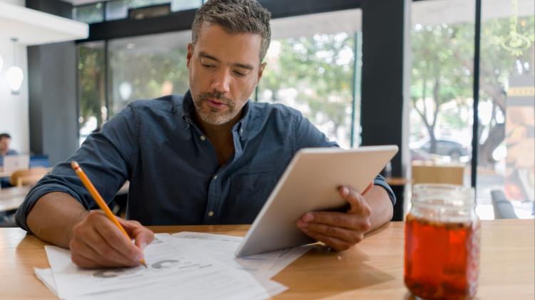 man business planning using tablet, paper, and pencil