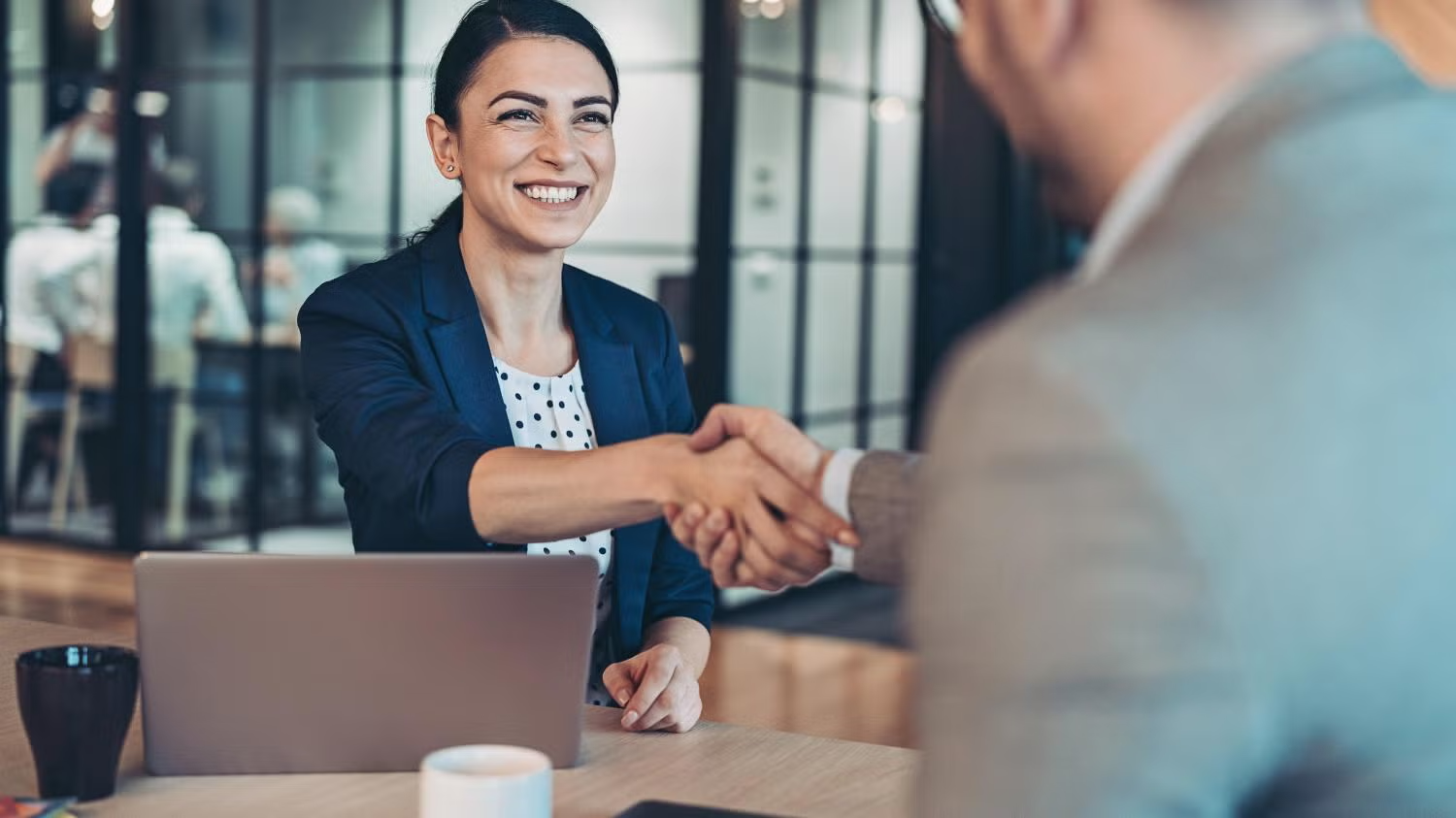 businesswoman shaking hands across table