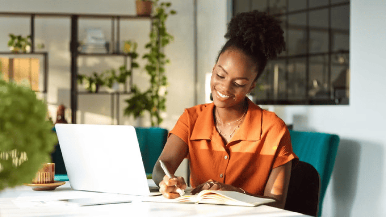 businesswoman taking notes while working at laptop
