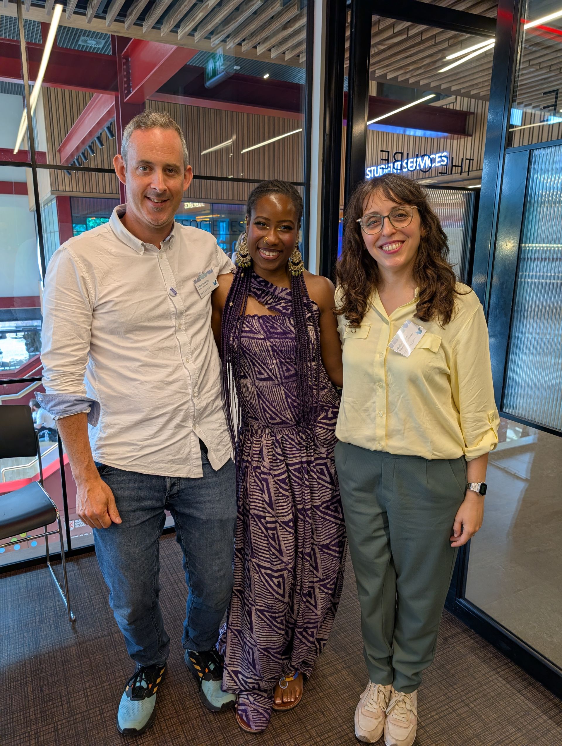 Three people standing with their arms around each other smiling