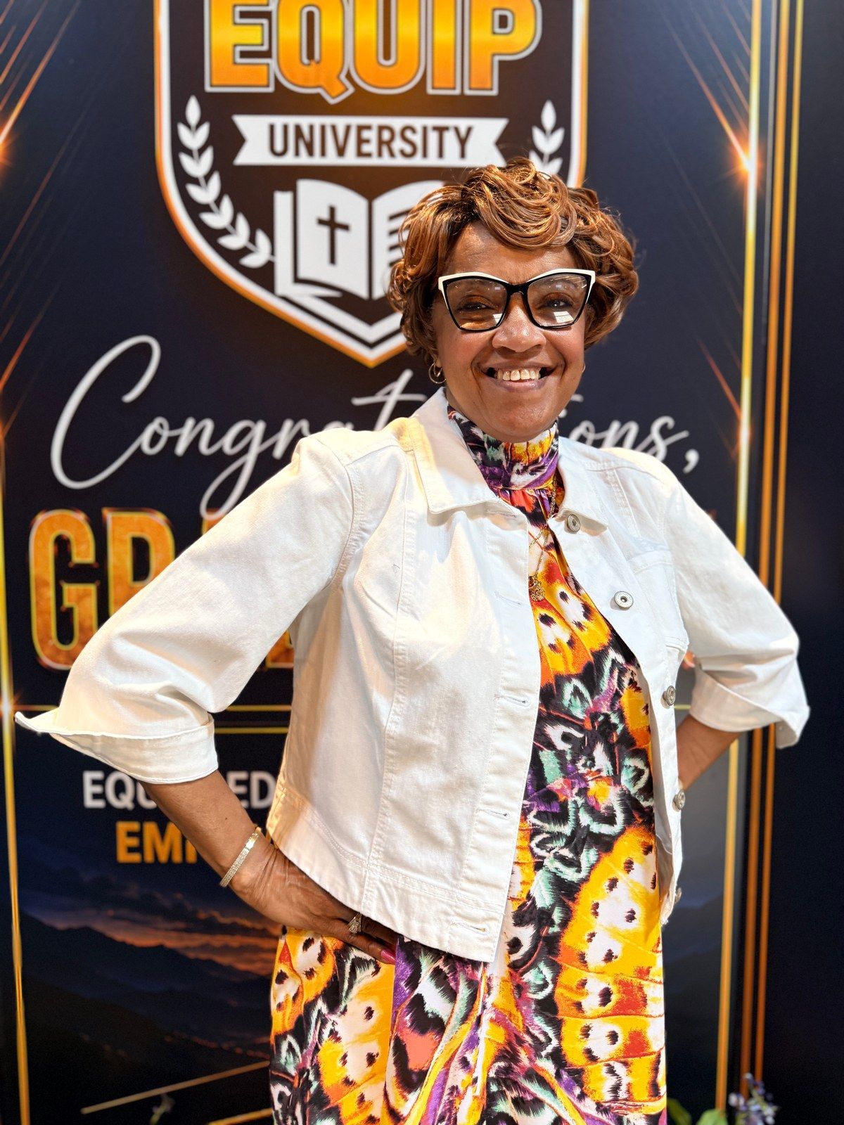 An EQUIP graduate celebrating in front of the graduation display