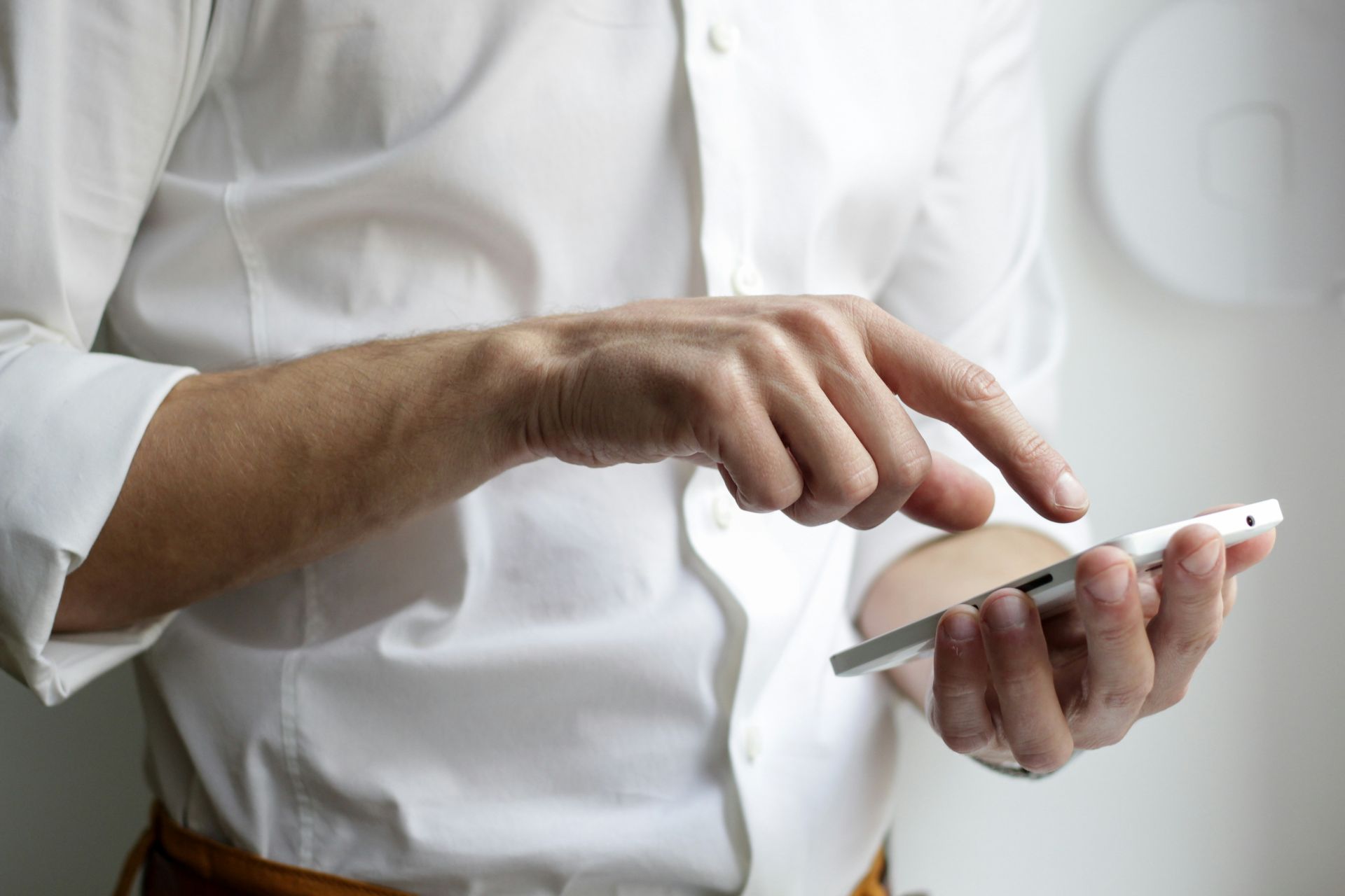 a person in a white shirt uses a smartphone, focusing on the screen.