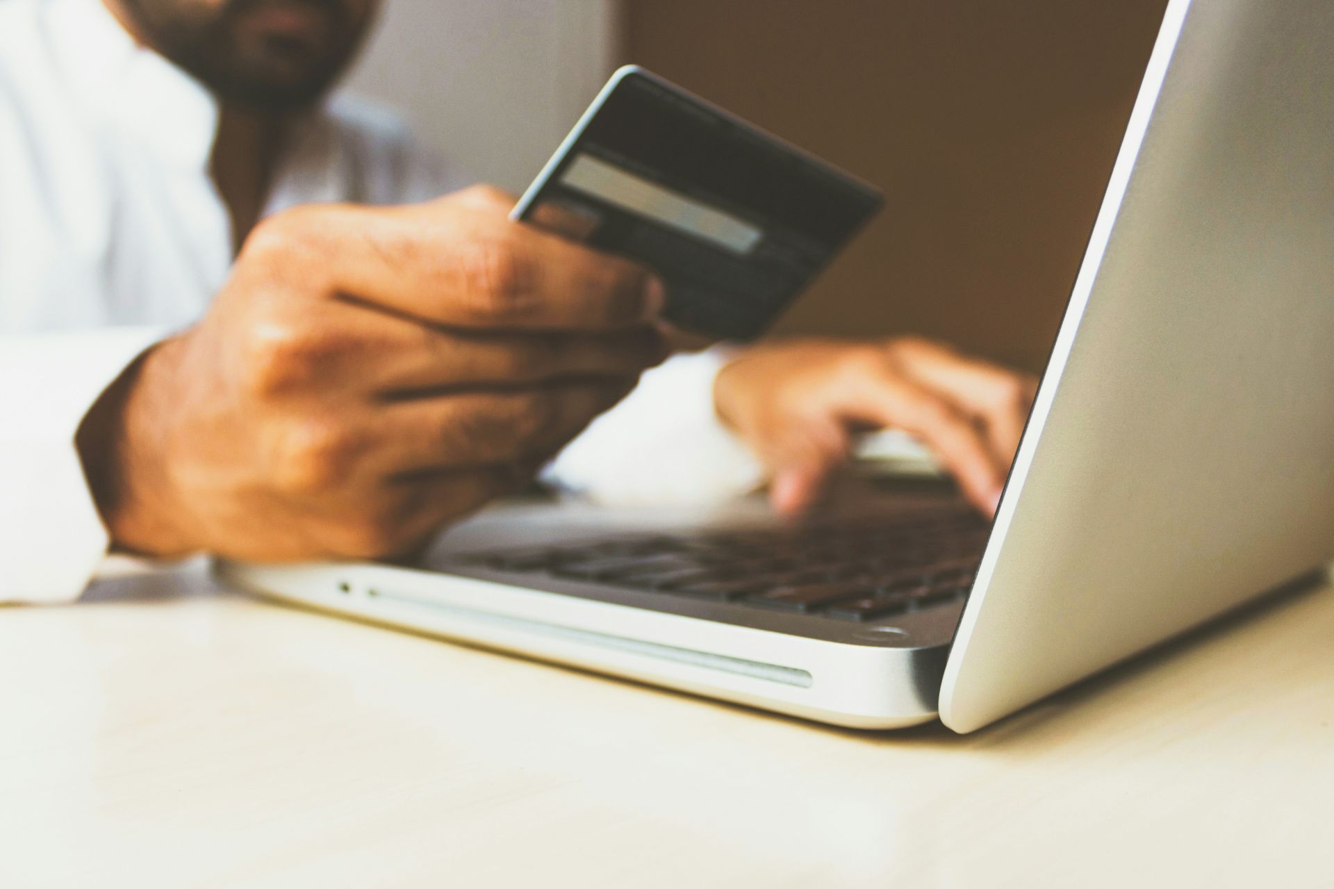  person holding a credit card while typing on a laptop