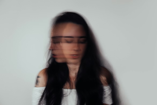 a blurred image of a woman with dark hair against a plain background, conveying a sense of anxiety.