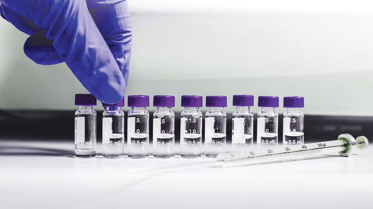 A purple gloved hand picking up a sample vial | Graphic for "Principles of HPLC Validation" course from Analytical Training Solutions