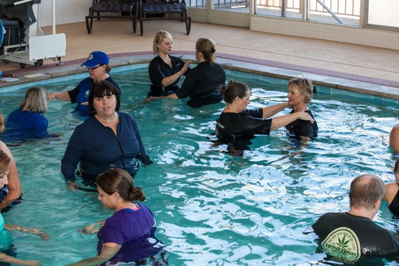 Therapists and clients work together in an indoor pool.