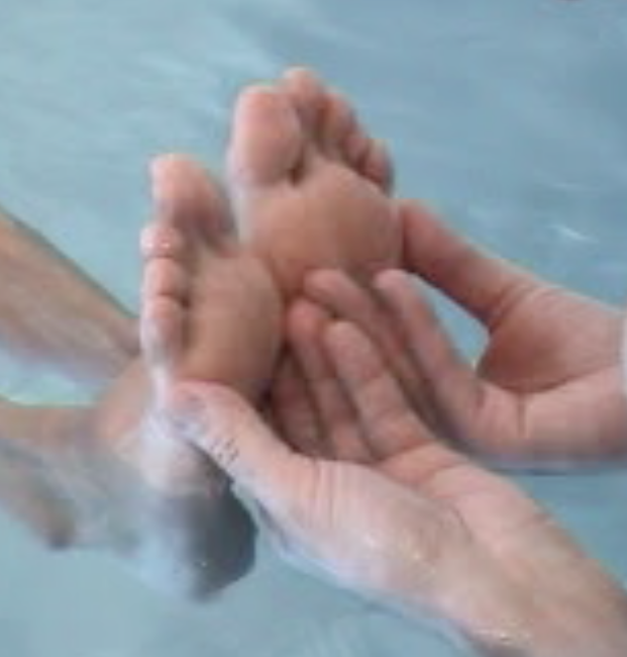 A therapist's hands hold a client's foot in the water.