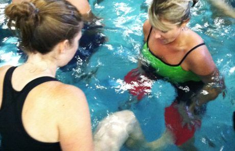 Two women exercise together in a pool.