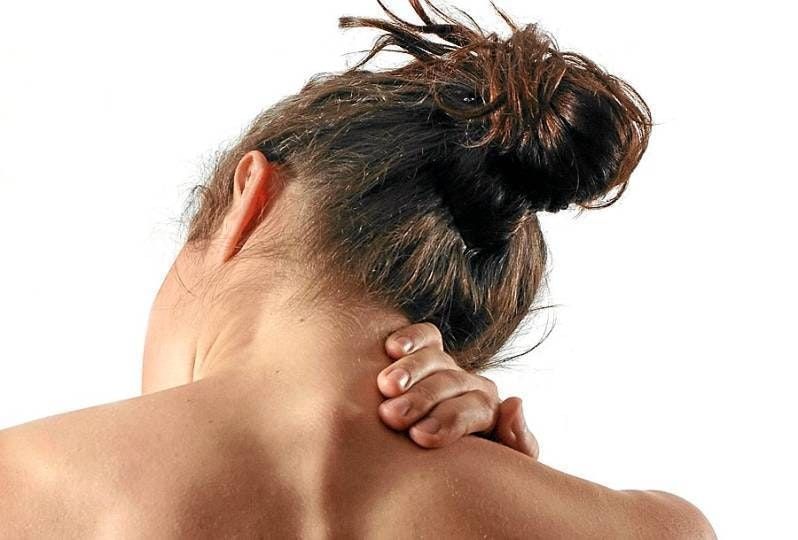 A woman holds the back of her neck.