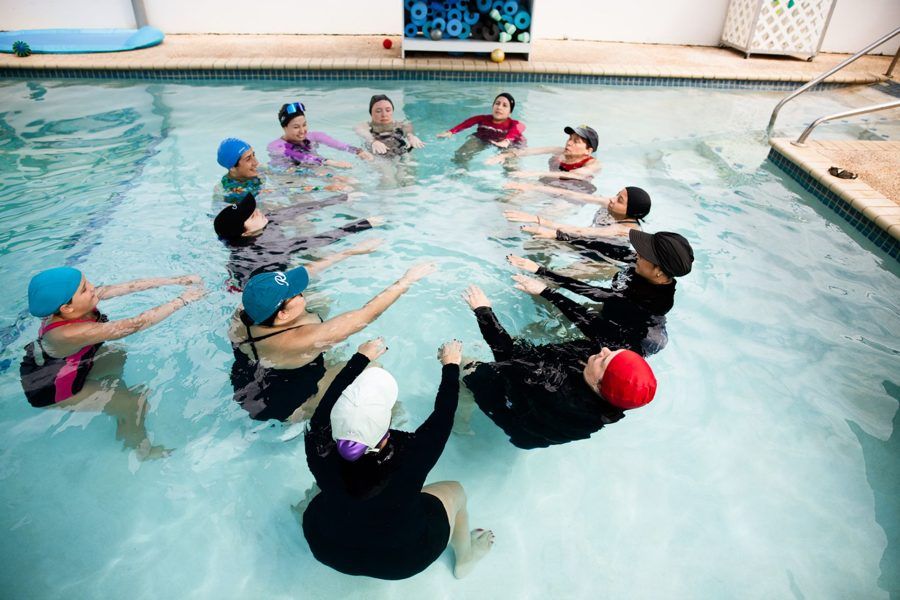 A team of therapists stands in a circle in a pool, practicing together during a group training