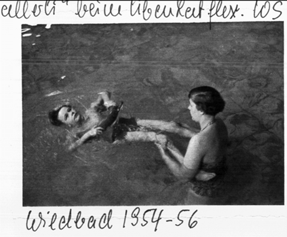 A black-and-white archive photo, labelled "Wildbad 1954-56", of a therapist working with a client who floats on rings.
