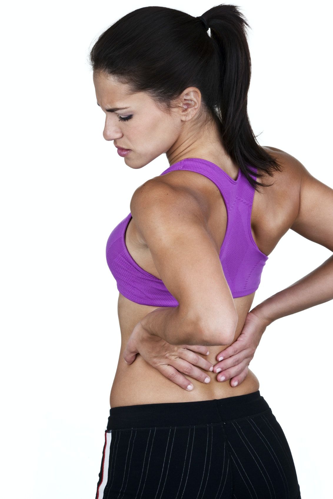 A woman in workout clothes holds her lower back.