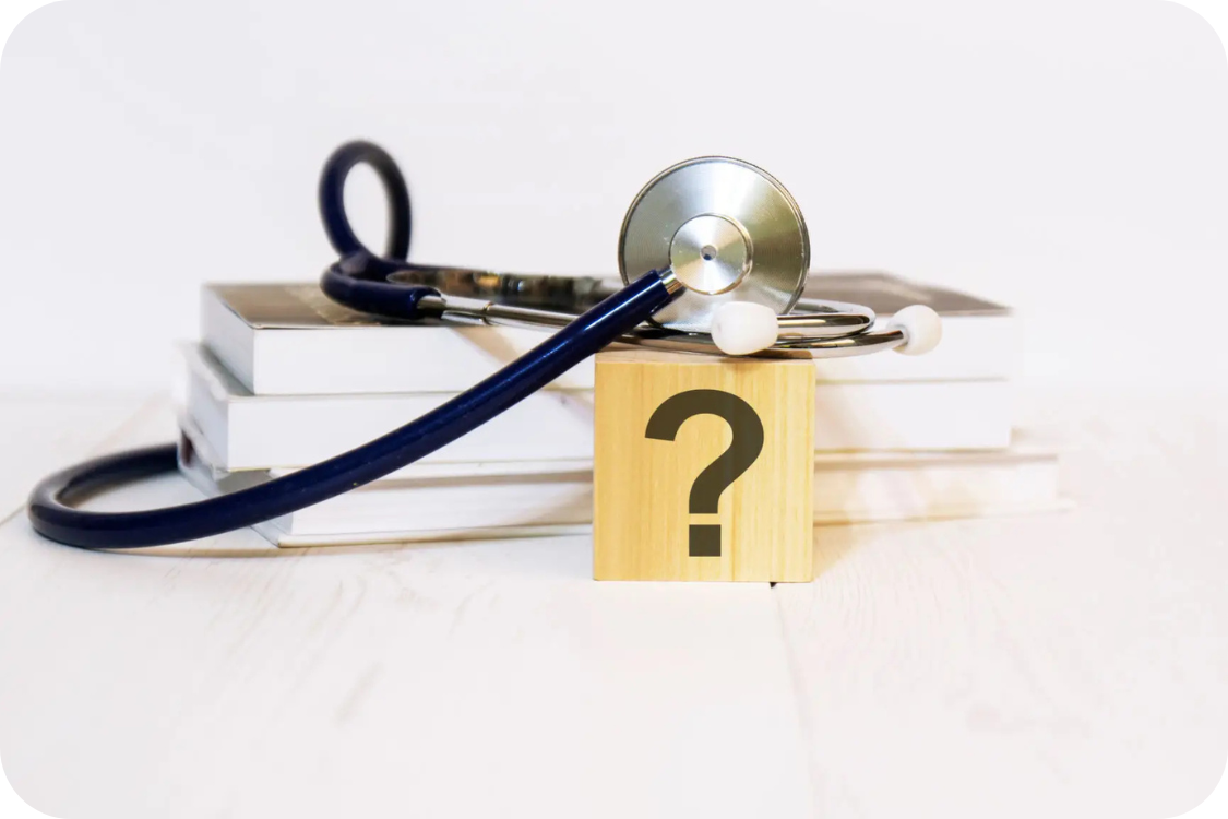 A stethoscope on a stack of books with a question mark in front of them