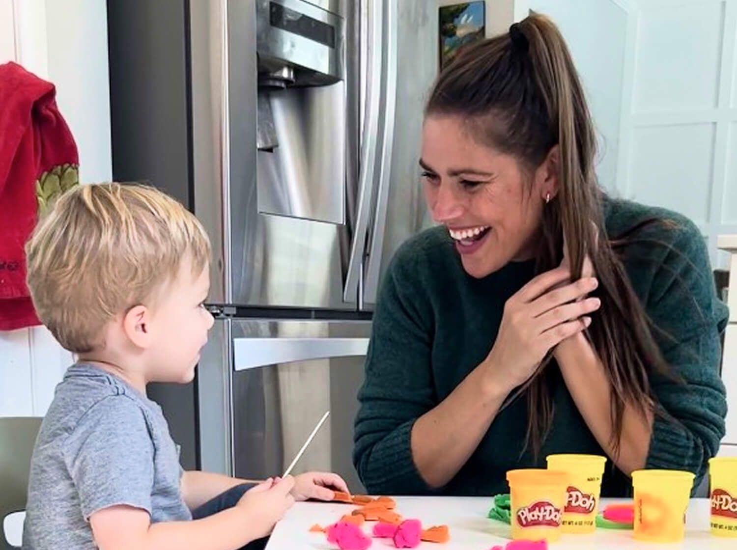 Kelly Goldberg, speech-language pathologist and early childhood education trainer sitting at toddler table with toddler playing playdough