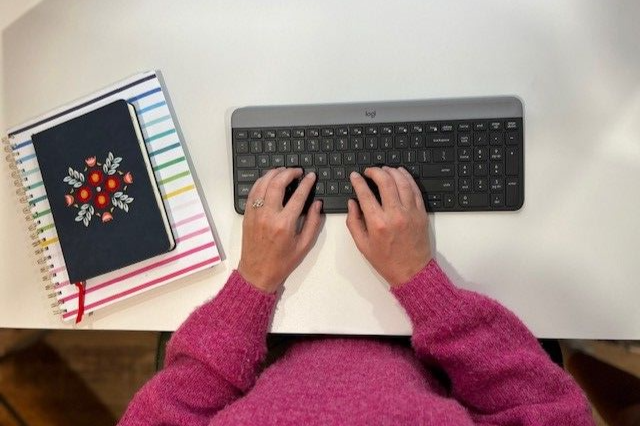 Hands over keyboard with planner to left