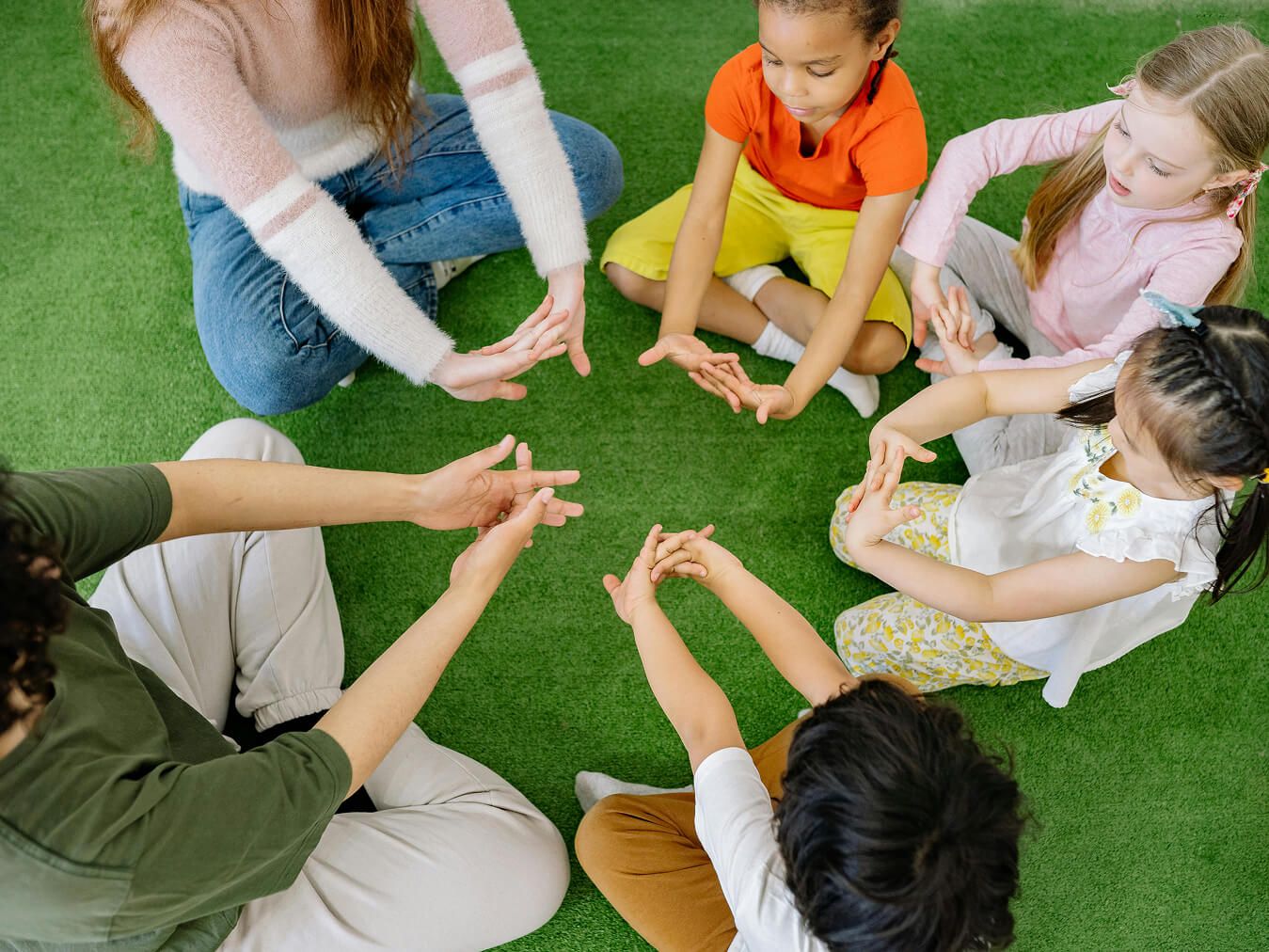 preschoolers sitting in circle with hands in center