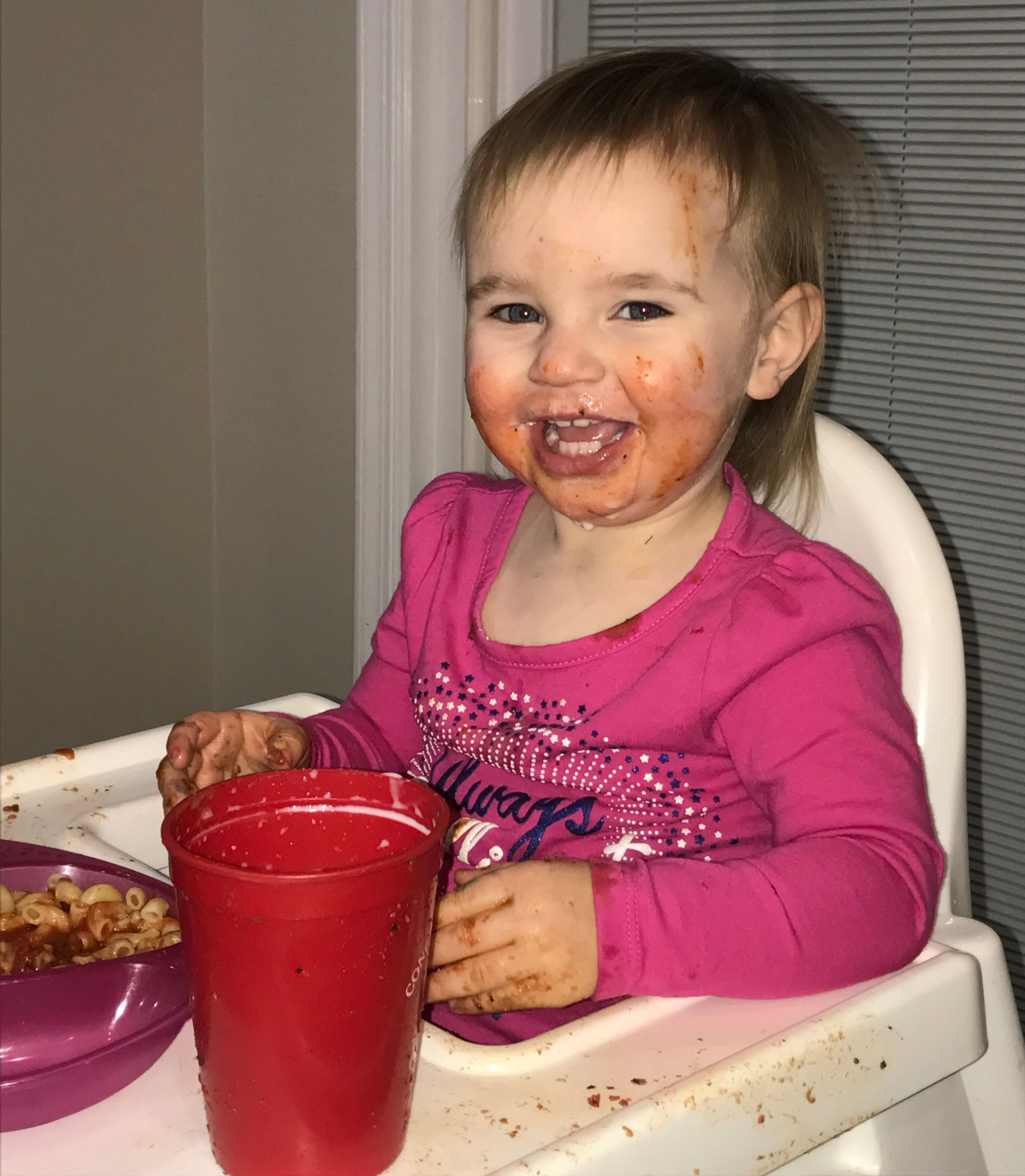 toddler in high chair with food in hand