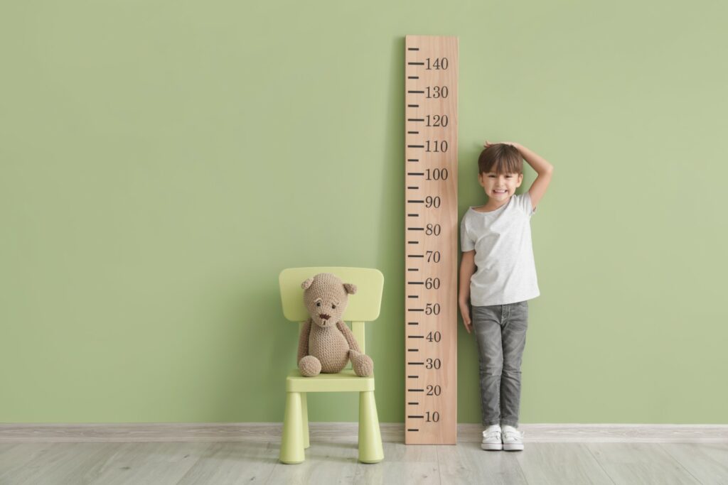 child measuring themselves against the wall
