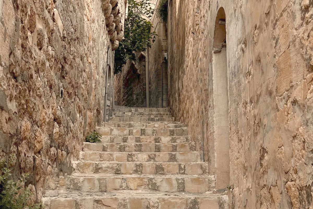 Old stone alley stairs climbing and turning out of sight, every tread dished from use