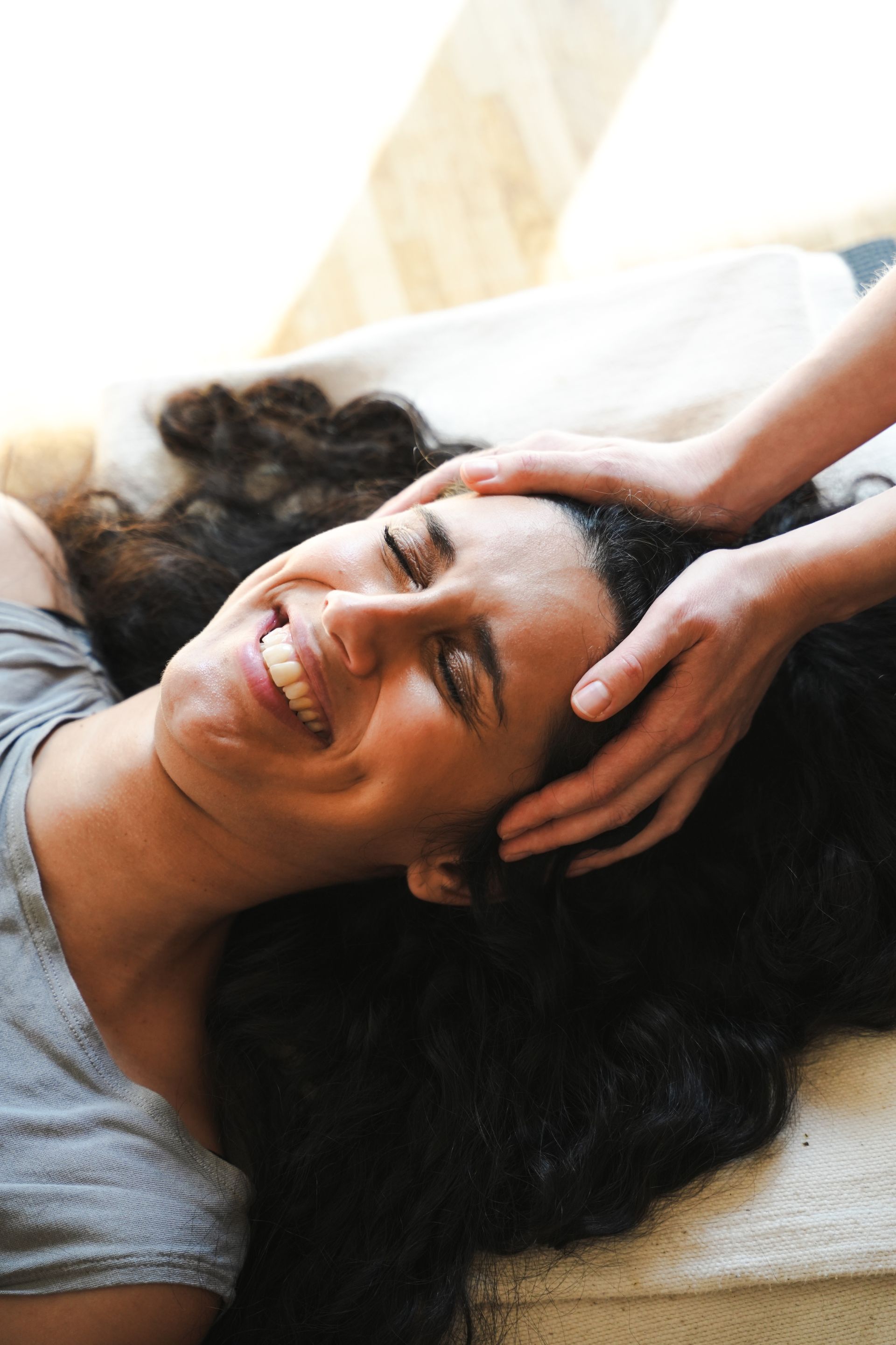 A smiling participant receiving gentle head support during breathwork