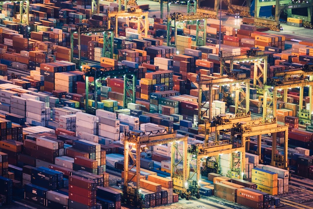 Aerial night view of stacked shipping containers at a busy port