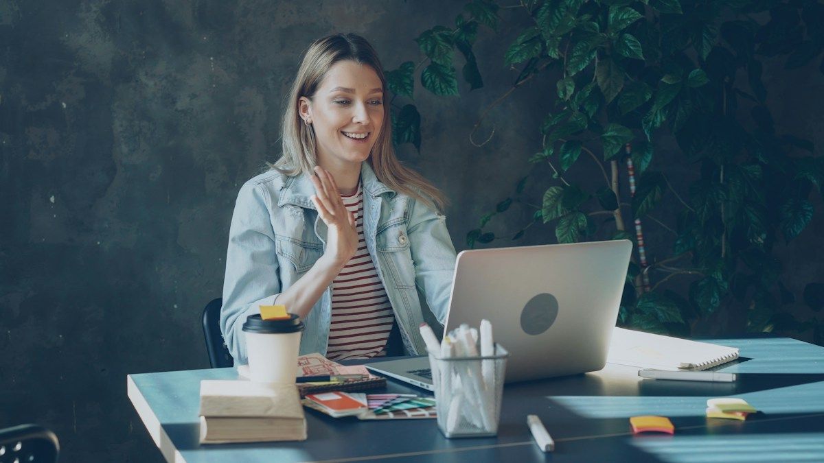 A woman participating in a video call at her desk. Illustrative stock photograph.
