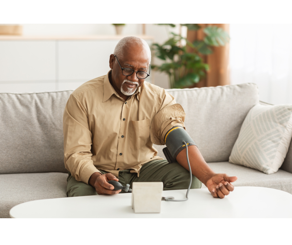 photo of black man taking his blood pressure sitting on a white couch